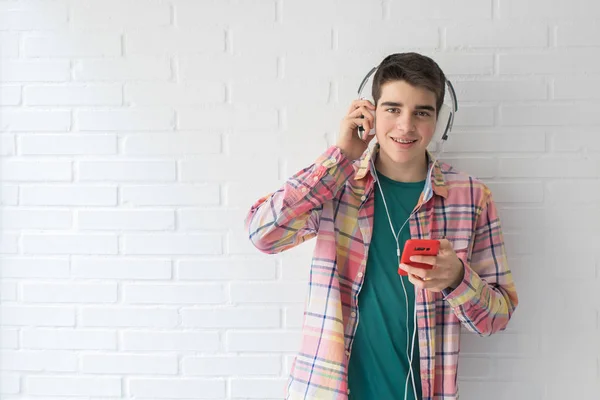 Νέος Έφηβος Κινητό Τηλέφωνο Και Ακουστικά Στο Λευκό Τοίχο — Φωτογραφία Αρχείου