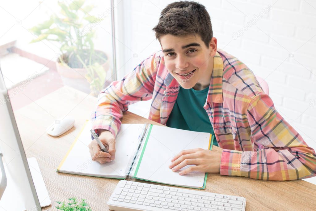 young student with computer on home desk or school