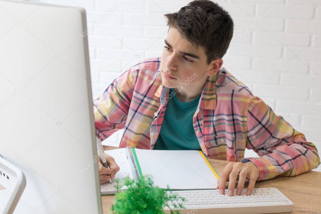 young student with computer on home desk or school