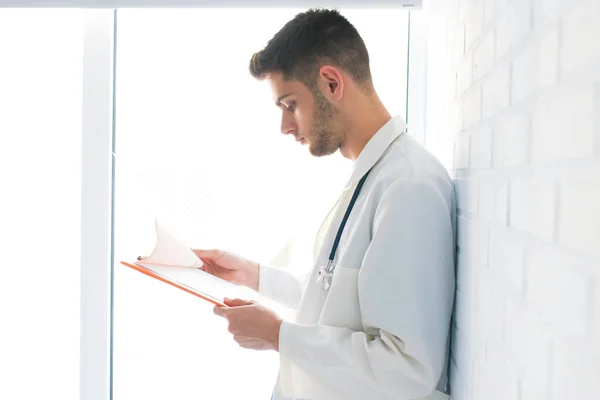 Γιατρός Κοιτάζοντας Έγγραφα Υπόβαθρο Που Υποστηρίζεται Στον Τοίχο Τούβλο — Φωτογραφία Αρχείου