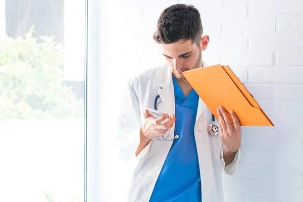 doctor at the clinic with a mobile phone and documents