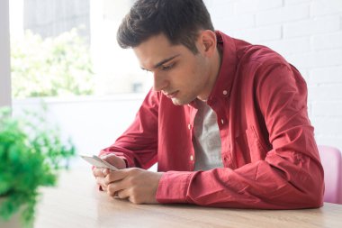 Masada ya da masada cep telefonu olan genç bir adam.