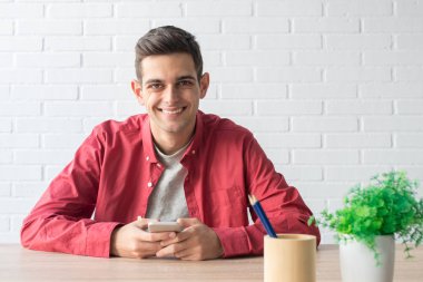 Evde ya da ofiste cep telefonu olan genç bir adam.