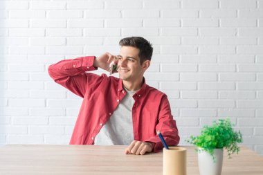 Cep telefonu evdeki masada duran genç adam.