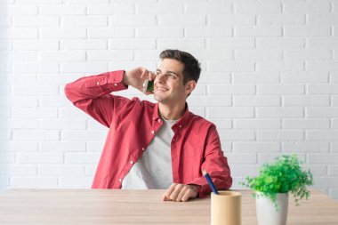 Cep telefonu evdeki masada duran genç adam.