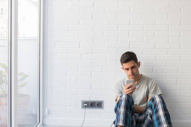 Sabahları cep telefonu olan genç bir adam.