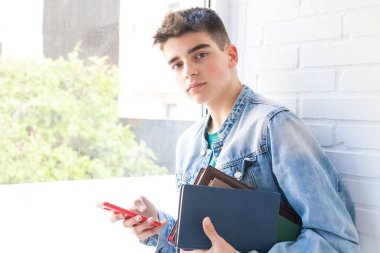 Kitapları ve cep telefonu olan öğrenci