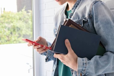 Kitapları ve cep telefonu olan öğrenci