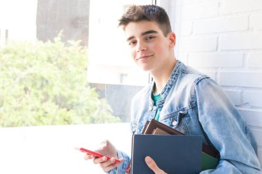 Kitapları ve cep telefonu olan öğrenci