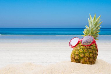 Sahilde güneş gözlüklü ananas.