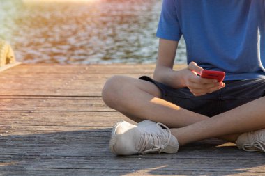 Gün batımında cep telefonu olan genç bir adam.