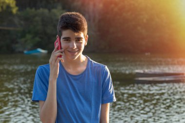 Gün batımında cep telefonu olan genç bir adam.