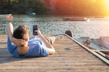 Gün batımında cep telefonu olan genç bir adam.