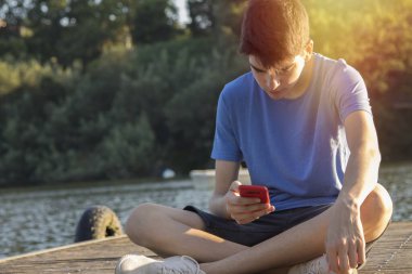 Gün batımında cep telefonu olan genç bir adam.