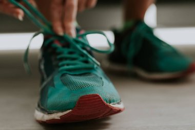 Koşucu spor yapmak için ayakkabısını bağlıyor.