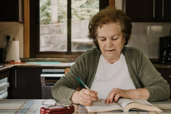 portrait of an older woman reading or with the crossword at home