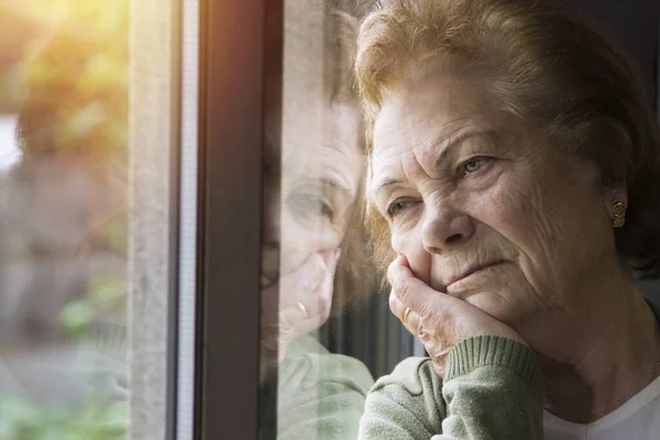 Portret Starszej Kobiety Wyglądającej Przez Okno — Zdjęcie stockowe