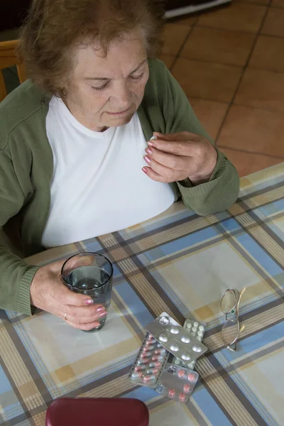 older woman taking medication at home