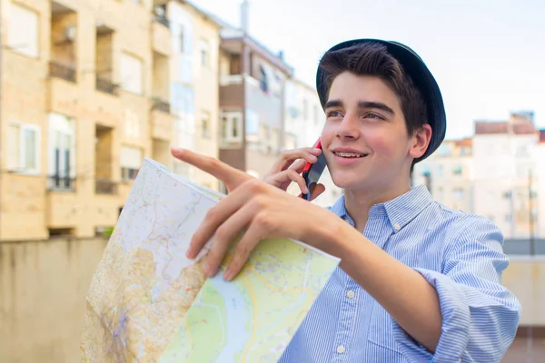 trendy young man with map and mobile phone on city street