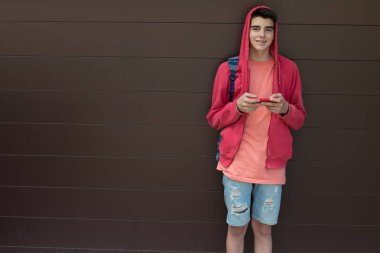 Duvarında cep telefonu ve sırt çantası olan bir öğrenci.