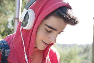 Dışarıda cep telefonu ve kulaklığı olan genç bir adam veya öğrenci.