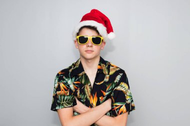 Arka planda tropikal tişörtü ve Noel şapkası olan genç bir kız.