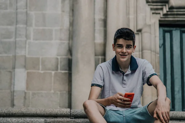 young teenage man with mobile phone in the city outdoors