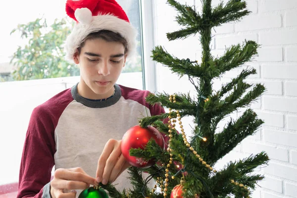 サンタ クラスの帽子をかぶった男の子クリスマスツリーを飾る — ストック写真