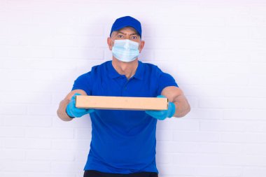 Arka planda maske ve eldivenli kurye ya da taşıyıcı var.