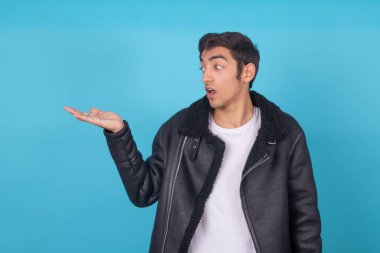 Renkli arka planda izole edilmiş genç adam elle işaret ediyor