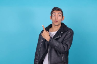Renkli arka planda izole edilmiş genç adam elle işaret ediyor