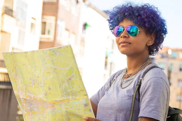 young african american girl with map and backpack with sunglasses in the city outdoors