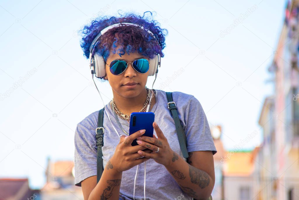 urban young girl with smartphone and headphones listening to music outdoors in the city