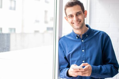 Genç adam akıllı telefonuyla evde.