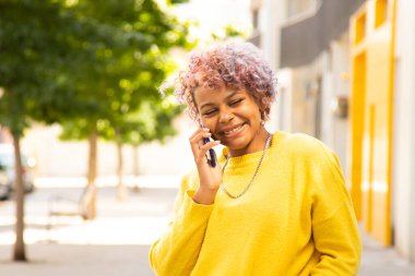 Şehirde cep telefonu olan gülümseyen genç kız.
