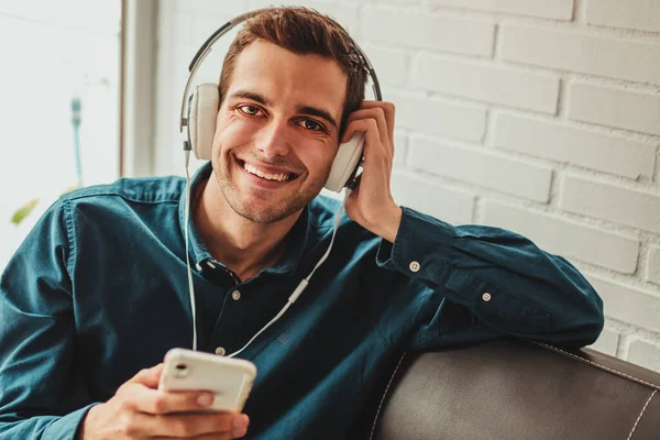 Χαμογελαστός Νεαρός Άνδρας Ακουστικά Και Κινητό Τηλέφωνο — Φωτογραφία Αρχείου