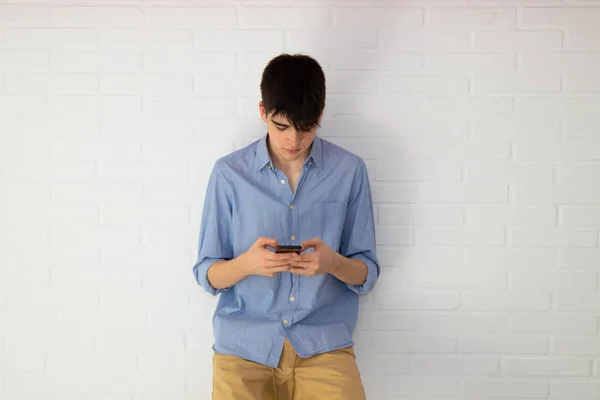 Mladý Teenager Muž Mobilním Telefonem Izolované Cihlové Zdi — Stock fotografie