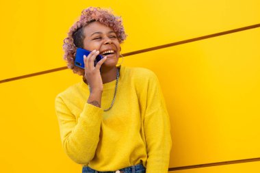 Sarı şehir duvarında cep telefonu olan mutlu kız.