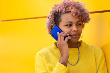 Sarı şehir duvarında cep telefonu olan mutlu kız.