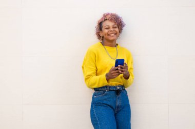 Sokak duvarında akıllı telefonu olan Afro-Amerikalı bir kız.