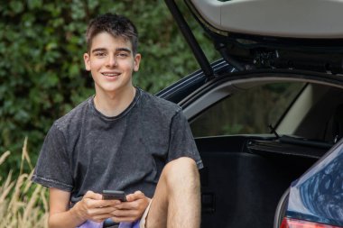 Arabasında gezmek ya da gezmek için cep telefonu olan genç bir adam.