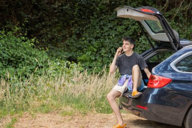 Arabasında gezmek ya da gezmek için cep telefonu olan genç bir adam.