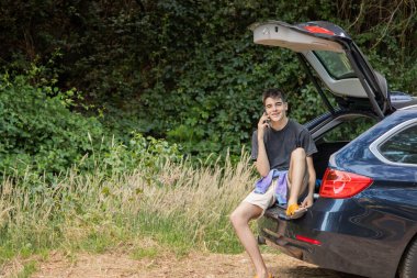 Arabasında gezmek ya da gezmek için cep telefonu olan genç bir adam.