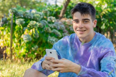 Dışarıda cep telefonu olan genç bir erkek.