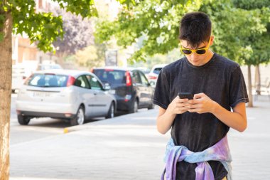 Şehirde cep telefonlu genç bir adam yürüyor.