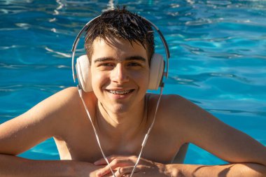 Havuzda kulaklık takan genç ya da erkek.