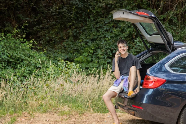 Arabasında gezmek ya da gezmek için cep telefonu olan genç bir adam.