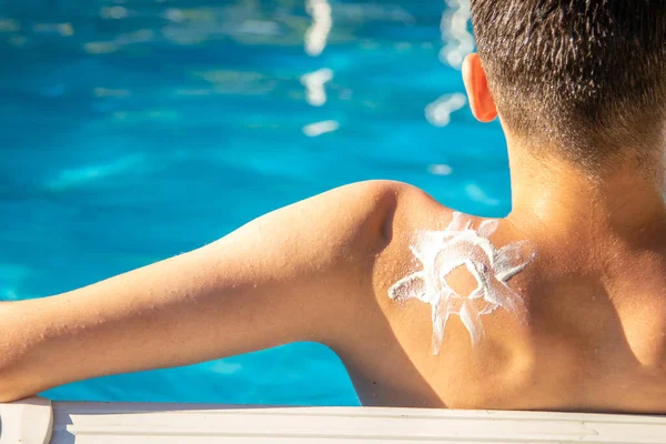 young man with sun cream sunbathing by the pool