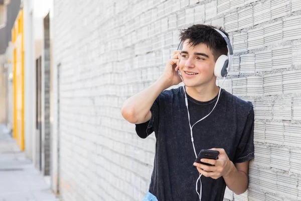 male teenager with headphones and phone on the street