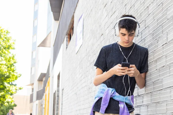 在街上带着手机和耳机的少年 — 图库照片